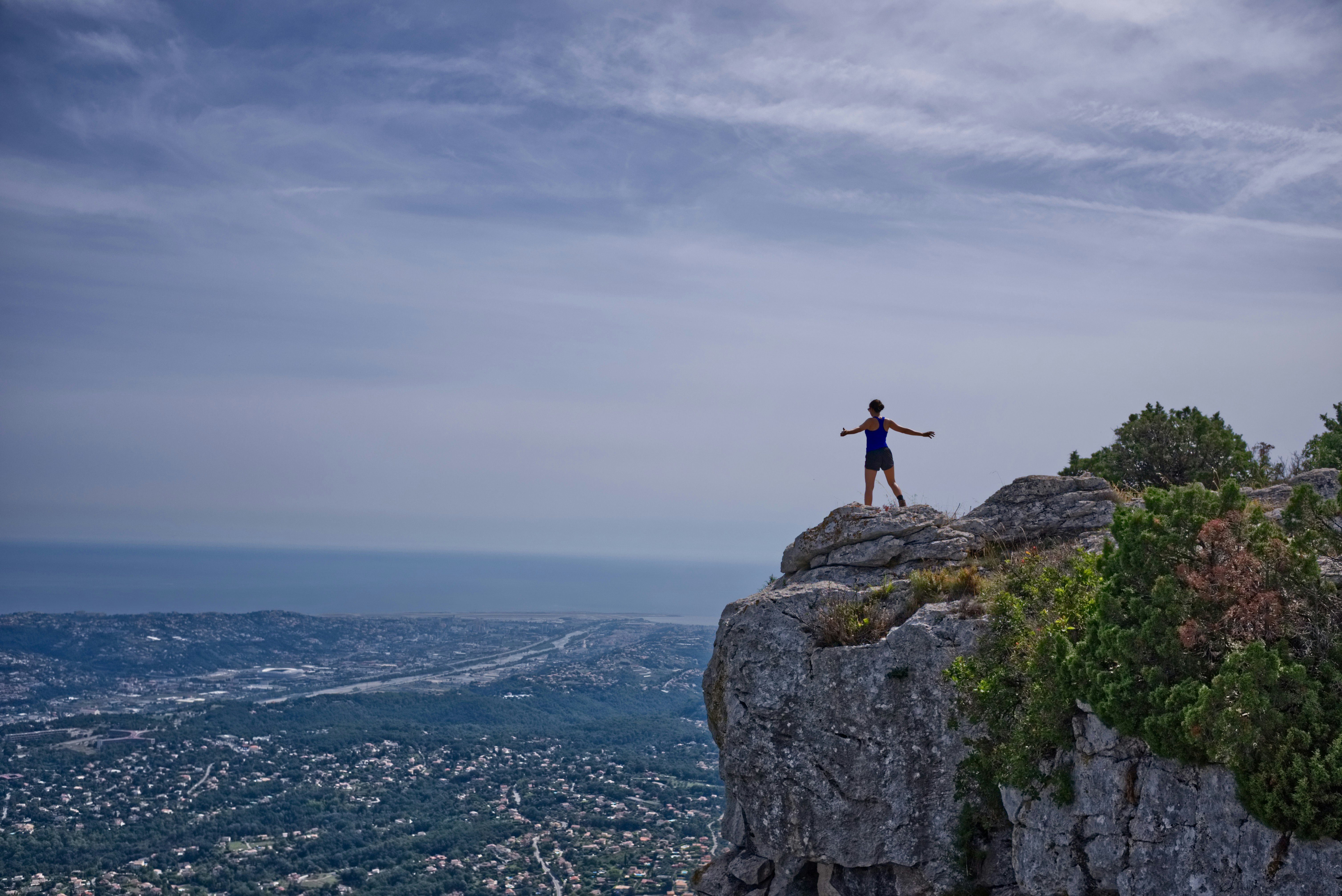 woman standing on cliff overlooking city during daytime